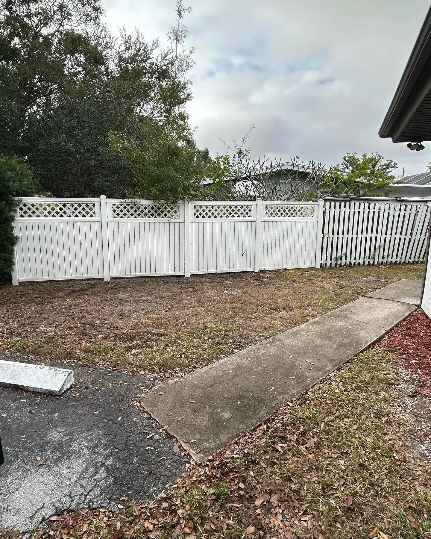 After view of a clean and cleared outdoor yard area with white fence following professional rubbish and debris removal service
