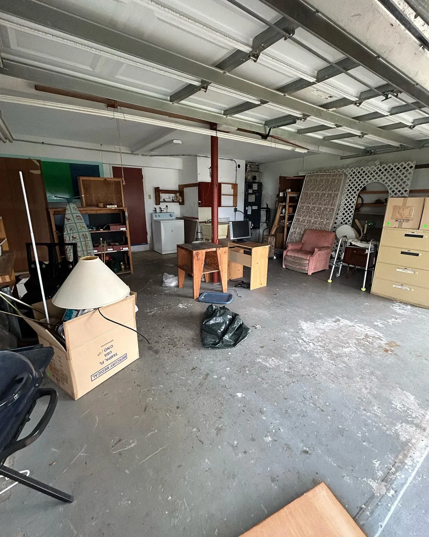Before view of a cluttered garage packed with furniture boxes and various junk items prior to professional clearance service