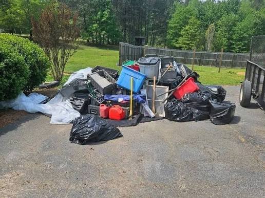 Cluttered residential garage in Gaffney SC filled with old furniture, storage boxes, and household junk awaiting removal